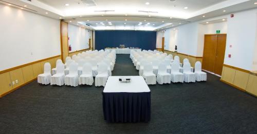 una sala de conferencias con sillas blancas y una mesa en el centro en Hotel Indigo La Paz Puerta Cortes, an IHG Hotel, en La Paz