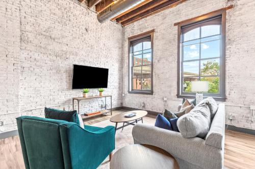 a living room with a couch and a tv at Brick & Bed Riverfront Lofts, PC 104 in Saint Louis