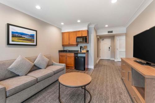 a living room with a couch and a flat screen tv at Best Western Plus Kelowna Hotel & Suites in Kelowna