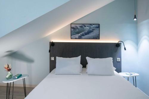 a bedroom with a large white bed with two tables at Best Western Alba in Nice