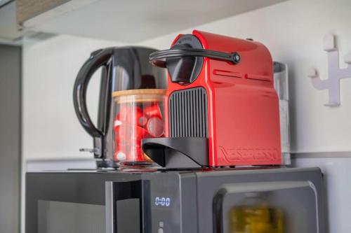 un mixeur rouge assis au-dessus d'un four micro-ondes dans l'établissement La Marquise - 3 Chambres, à Reims
