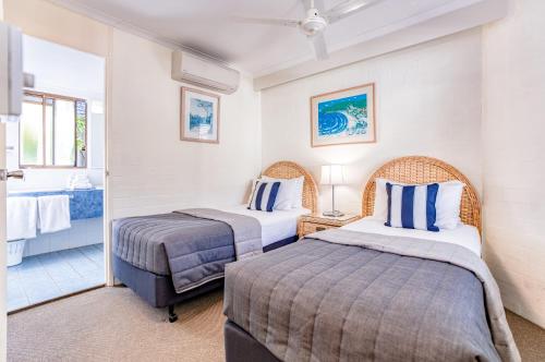 a hotel room with two beds and a bathroom at Ocean Breeze Resort in Noosa Heads