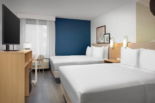 ein Hotelzimmer mit 2 Betten und einem TV in der Unterkunft Spark by Hilton Atlanta Cumberland Ballpark in Atlanta