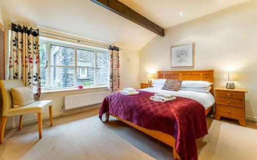 una camera da letto con un letto, una sedia e una finestra di Studio Cottage ad Ambleside