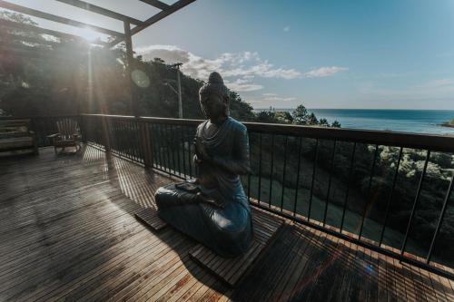 a statue of a woman sitting on a balcony looking at the ocean at Casa Yogui Brasil in Garopaba