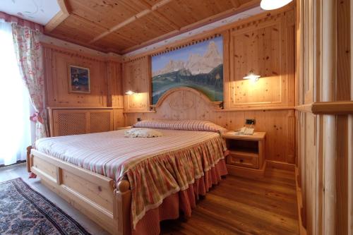 a bedroom with a bed and a painting on the wall at Hotel Letizia in San Martino di Castrozza