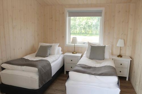 a bedroom with two beds and a window at Miðhraun - Lava resort in Midhraun
