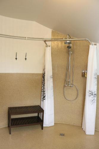 a bathroom with a shower with curtains and a bench at Miðhraun - Lava resort in Midhraun