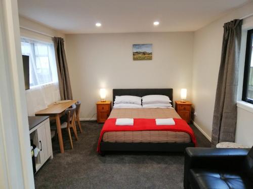 a bedroom with a bed and a table and a desk at Judges Pool Motel Turangi in Turangi