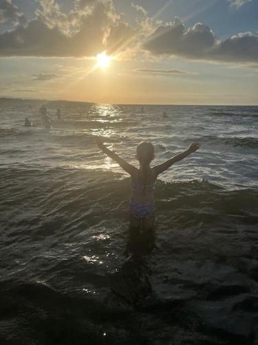 a young girl standing in the ocean with her arms out at House in the Burren Clare in Droíchead an Chláir