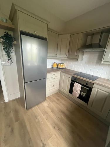 a kitchen with a stainless steel refrigerator and white cabinets at House in the Burren Clare in Droíchead an Chláir