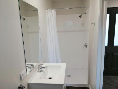 a white bathroom with a sink and a mirror at Judges Pool Motel Turangi in Turangi