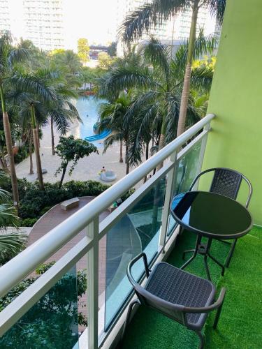 balcón con mesa, sillas y piscina en LizJen Staycation at Azure Urban Resort, en Manila