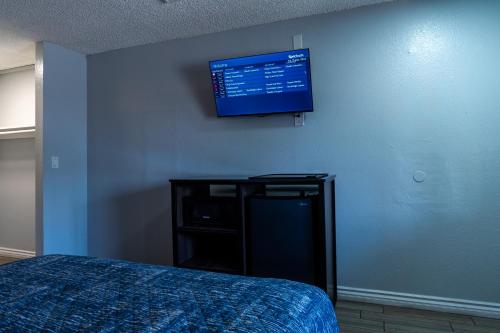a bedroom with a bed and a flat screen tv on the wall at Pala Motel in Pomona