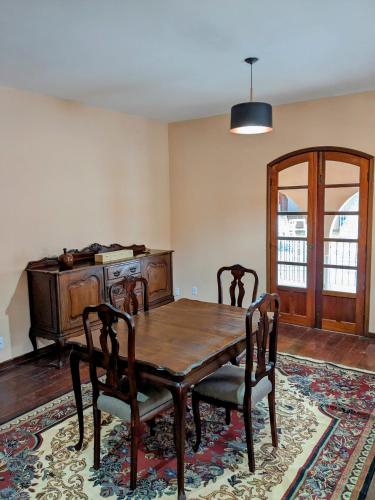 a dining room with a wooden table and chairs at Casa Central Hospedagem in Miguel Pereira