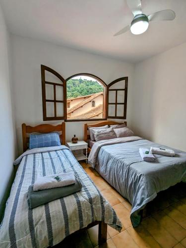 two beds in a bedroom with a window at Casa Central Hospedagem in Miguel Pereira