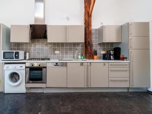 a kitchen with white cabinets and a washer and dryer at Het Grootenhuis in Olst