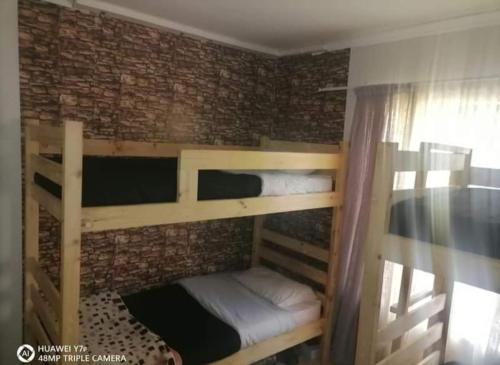 two bunk beds in a room with a brick wall at Secunda BackPackers in Secunda