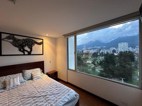 a bedroom with a large window with a view of a city at Five Stars Suites - Park - Quito in Quito