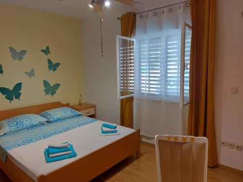 um quarto com uma cama e uma janela com borboletas na parede em Apartments with a parking space Postira, Brac - 2911 em Postira