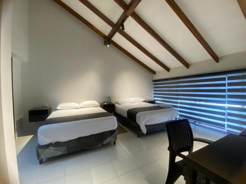 a bedroom with two beds and a table and a chair at Amaca Hostal in Santa Cruz de la Sierra