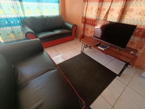 sala de estar con sofá y TV de pantalla plana en Kapeta Cabin, en Hofoa