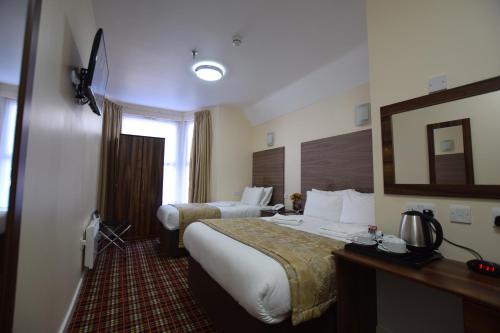 a hotel room with two beds and a mirror at Lucky 8 Hotel in Ilford