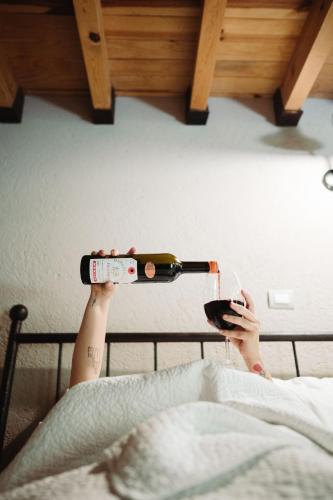 a person laying in bed holding a bottle of wine at María & Bernardo Casa - Viñedo in El Coyote