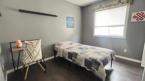 a bedroom with a bed and a table and a window at Private Room Male Only North Side Edmonton 165 Ave 56 Street Walking Distance to Strip Mall in Edmonton