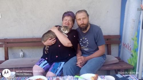 un hombre y una mujer sentados en un banco sosteniendo un gato en Family owned self sufficient ECO farm TARA en Pljevlja