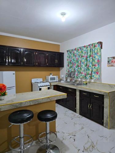 une cuisine avec un comptoir et deux tabourets de bar dans l'établissement Cozy private APT in La Ceiba, à La Ceiba