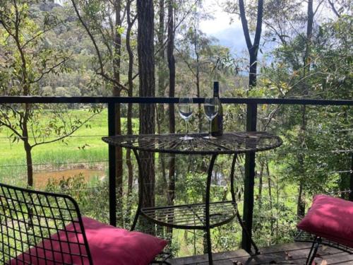 a table with a glass of wine on a balcony at Nature Retreat & Artists Studio 90mins from Sydney in Spencer