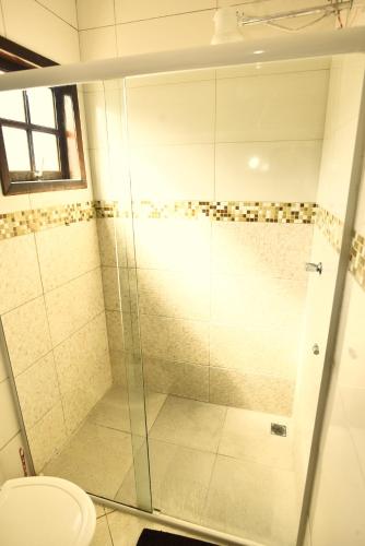 a bathroom with a glass shower with a toilet at Apto bem equipado, com 2 quartos acomoda até 6 pessoas confortavelmente in Ubatuba