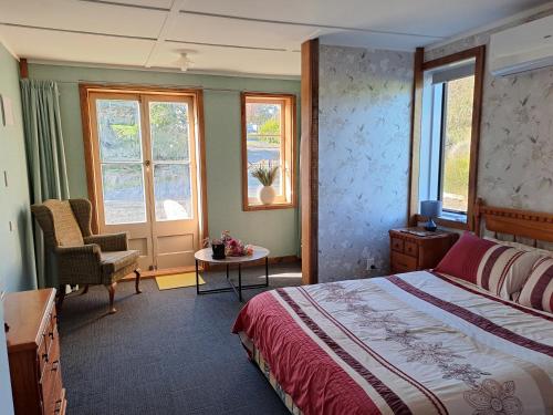 a bedroom with a bed and a chair and windows at Fieldview Arapuni B&B in Putaruru