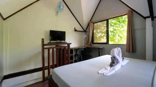 Un dormitorio con una cama y un televisor y una ventana. en The Piupiu Nest, en Iriga City