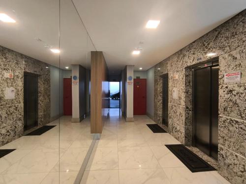 un pasillo de un edificio de oficinas con puerta de cristal en Ivana Imoveis - Grupo de Aptos Temporada - Praia do Morro, en Guarapari