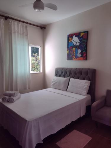 a bedroom with a large bed and a chair at Aconchego Mineiro in São João del Rei