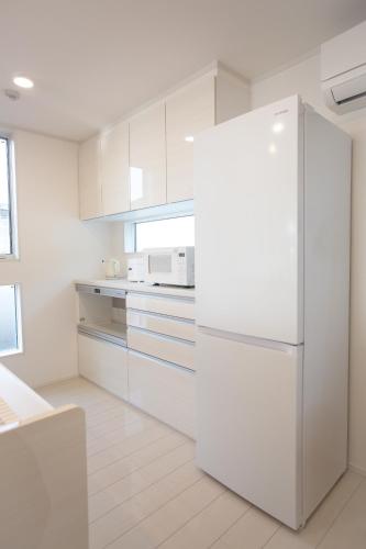 a white kitchen with a white refrigerator in it at Ashina Bayfront Villa in Yokosuka