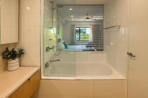 a bath tub with a glass shower in a bathroom at Oceania at Darwin Waterfront in Darwin