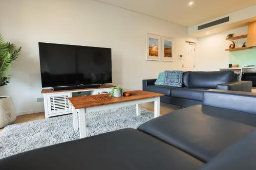 a living room with a large flat screen tv at Oceania at Darwin Waterfront in Darwin