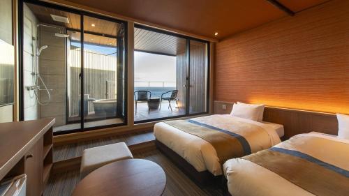 a bedroom with two beds and a view of the ocean at Umiusagi in Higashiizu