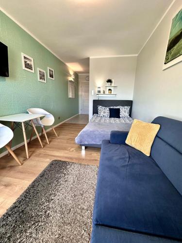 a living room with a blue couch and a bed at Pod Papugami - Komfortowe pokoje z widokiem na rzekę in Łeba
