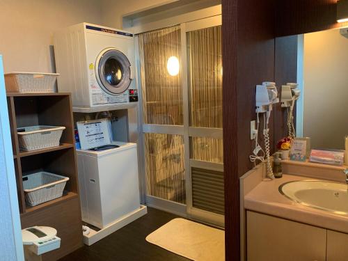 a bathroom with a sink and a washing machine at Hotel Route-Inn Hitachitaga in Hitachi