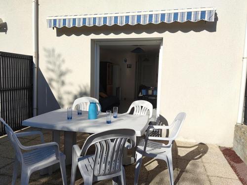 une table avec des chaises blanches et une tasse bleue dessus dans l'établissement Maison calme avec jardin, à 500m de la plage, proche commerces, bien équipée pour 4 personnes - FR-1-639-19, à Sarzeau
