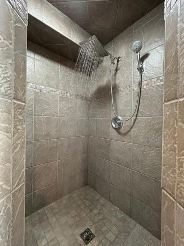 een douche in een betegelde badkamer met een douchekop bij Iowa Nice, Winterset in Winterset