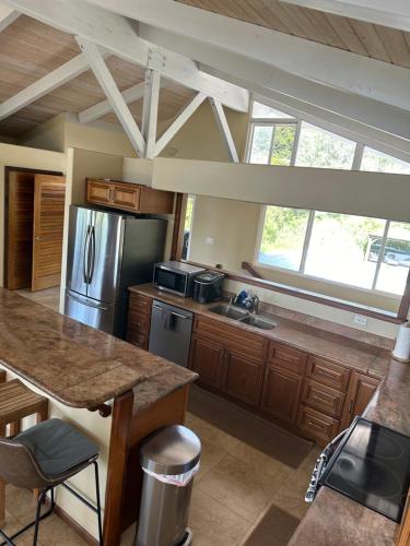 a large kitchen with a stainless steel refrigerator at Ocean views, indoor and outdoor brilliance! in Haleiwa