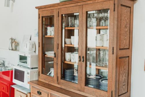 a wooden cabinet with plates and dishes in it at Hakuba Log Hotel Meteor in Hakuba