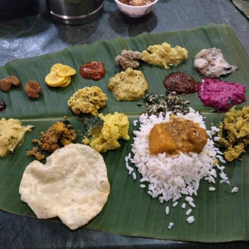 a plate of food on a banana leaf with rice at Bhuvanam homestay in Kalpetta