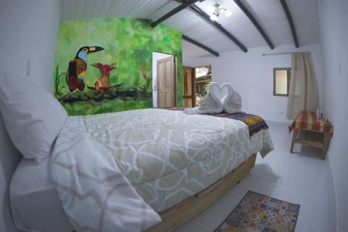 ein Schlafzimmer mit einem großen Bett und einem Gemälde an der Wand in der Unterkunft Birdwatchers House y Lodge in Mindo