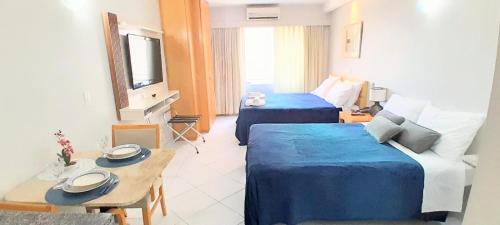 a hotel room with two beds and a table at Flat em frente ao Allianz Parque - Com Estacionamento in São Paulo